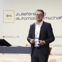 Hans Remsig, Leiter Expertenteam Automotive bei der Deutschen Bank, steht auf der Bühne beim Zulieferertag Automobilwirtschaft BW 2021 und hält einen Impuls.