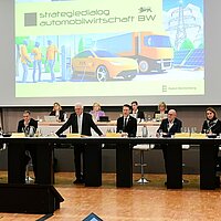 Ministerpräsident Winfried Kretschmann eröffnet das Top-Level-Meeting. auf dem Strategiedialog Automobilwirtschaft BW. Er ist umgeben von anderen wichtigen Vertreter:innen der Industrie.