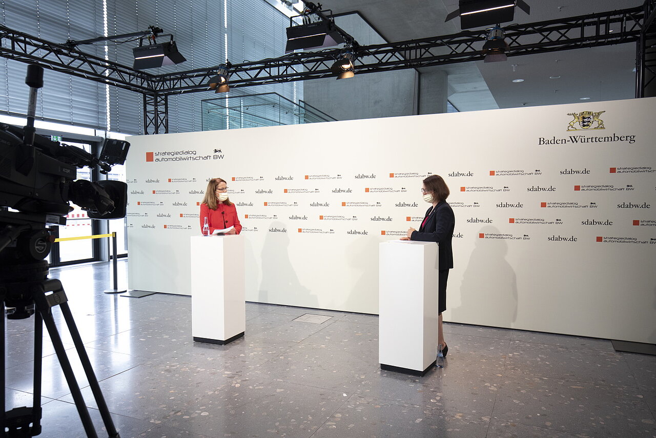 Mitarbeiterin von e-mobil BW berichtet einer anderen Person über die neue Landeslotsenstelle Transformationswissen BW und wird dabei gefilmt.