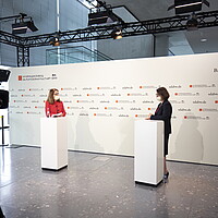 Mitarbeiterin von e-mobil BW berichtet einer anderen Person über die neue Landeslotsenstelle Transformationswissen BW und wird dabei gefilmt.