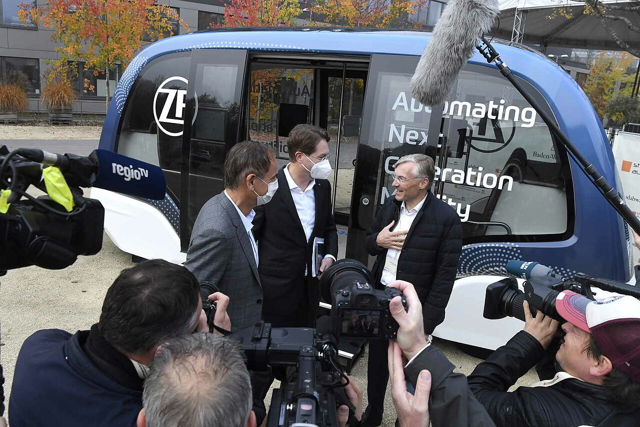 Wirtschaftsvertreter: innen im Gespräch vor einem autonomen Shuttle bei der SDA-Jahresveranstaltung.