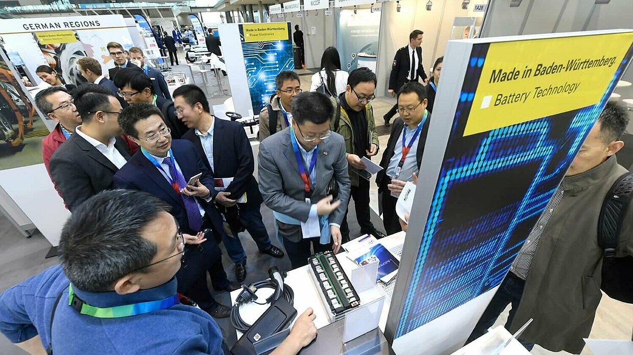 Bild der Hannover Messe Ein Stand auf einer Messe, mehrere Menschen stehen um den Stand herum.