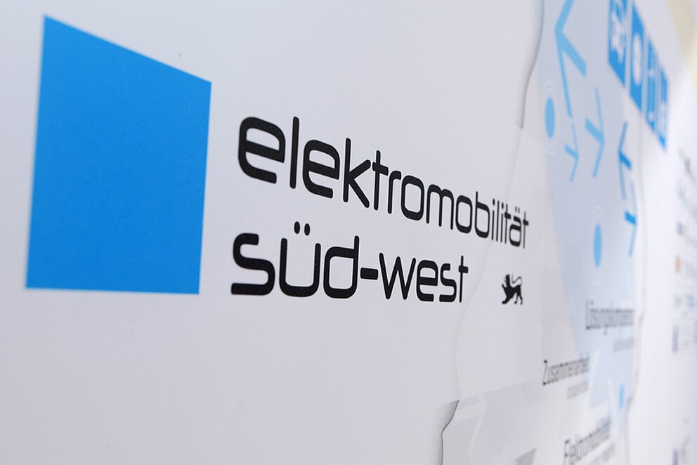 Logo des Clusters Elektromobilität Süd-West von der Seite auf einer Wand fotografiert