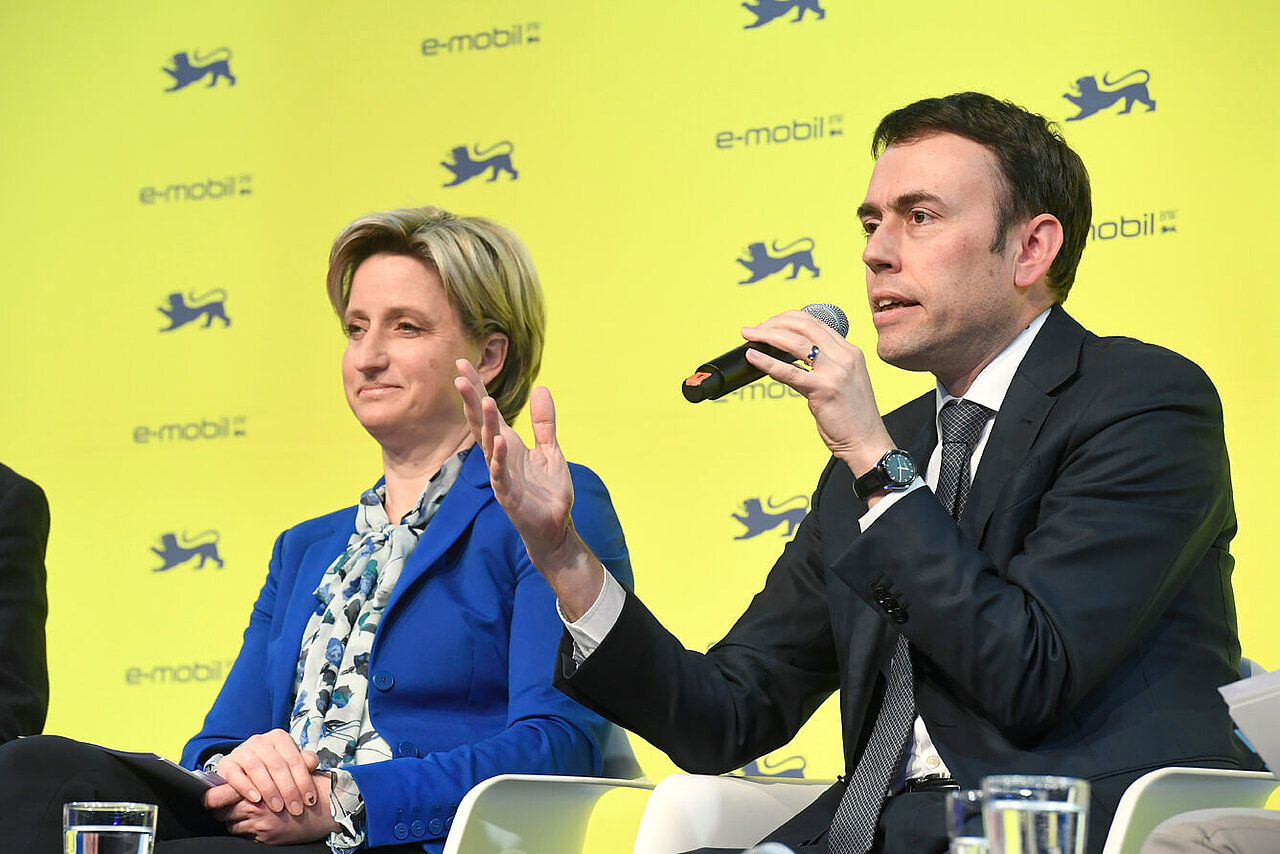 Dr. Nils Schmid MdB und Wirtschaftsministerin Dr. Nicole Hoffmeister-Kraut MdL auf dem Podium. Dr. Nils Schmid spricht in ein Mikrofon und hält die Hand hoch.
