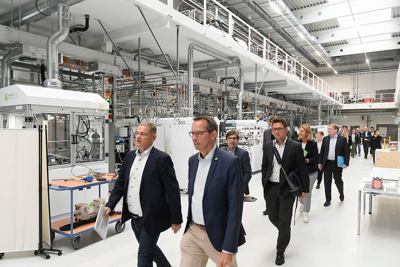 Eine Besuchergruppe läuft durch eine Fabrikhalle mit Testständen für Brennstoffzellenstacks.