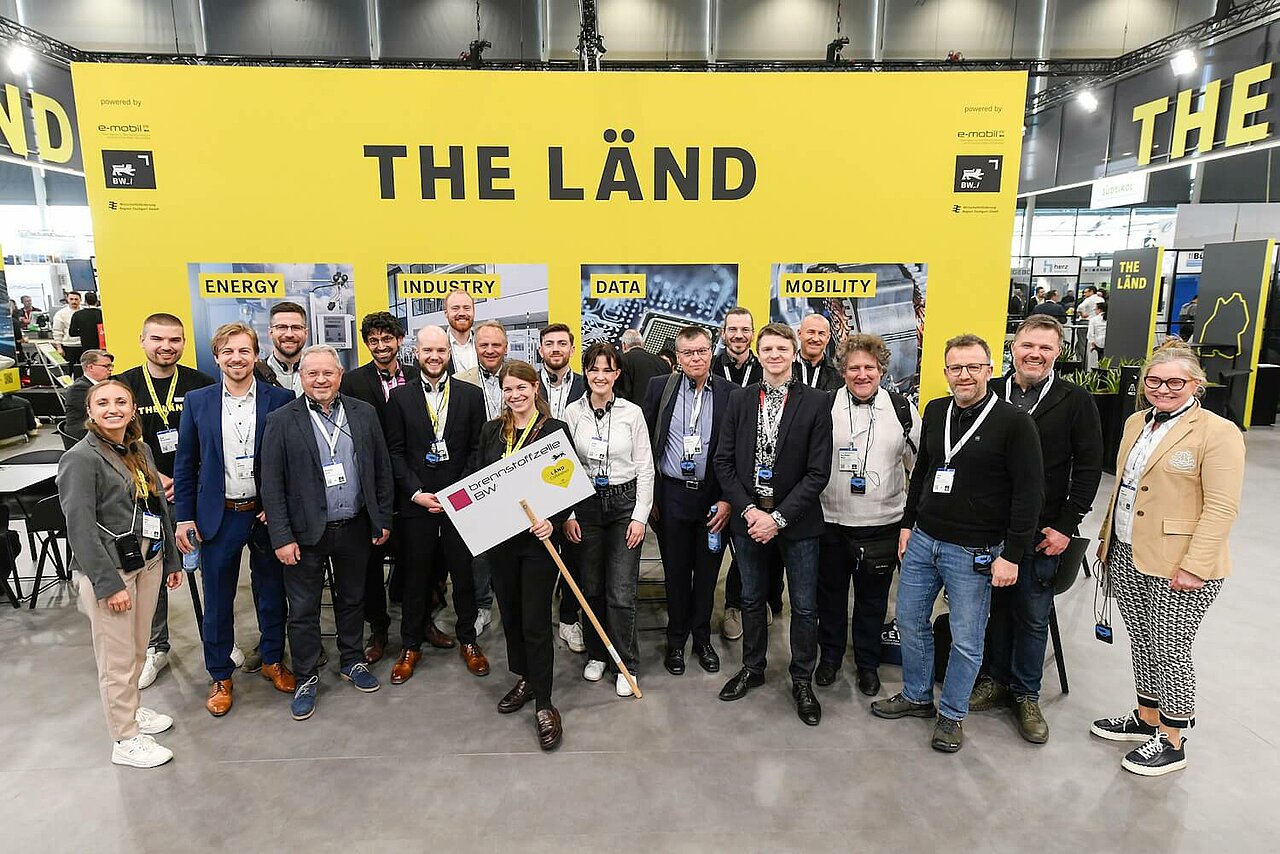 Eine Gruppe von Menschen vor einer gelbes Messewand auf der Hannover Messe.