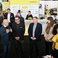Verkehrsminister Winfried Hermann spricht in ein Mikrofon auf der i-Mobility am Stand von e-mobil BW.