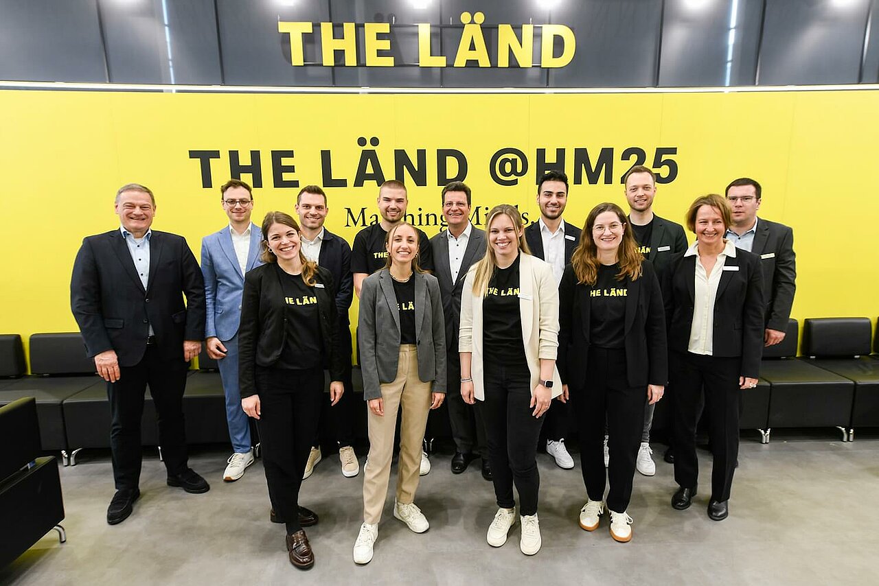 Gruppenfoto mit Mitarbeiterinnen und Mitarbeitern der e-mobil BW GmbH am Messestand von THE LÄND auf der Hannover Messe.