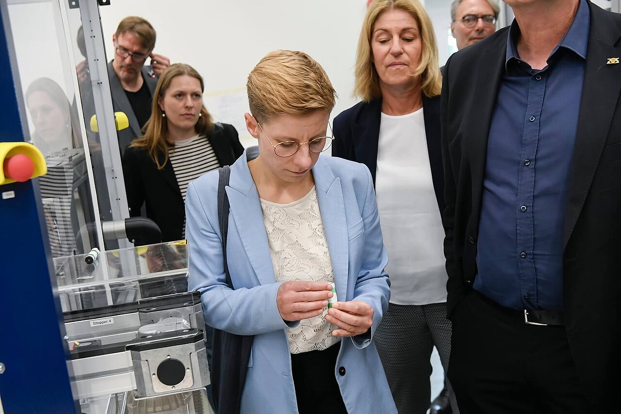 Eine Frau hält ein Gehäuse einer Pouchzelle in den Händen.