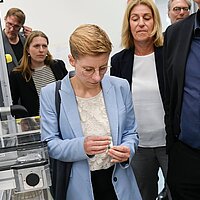 Eine Frau hält ein Gehäuse einer Pouchzelle in den Händen.