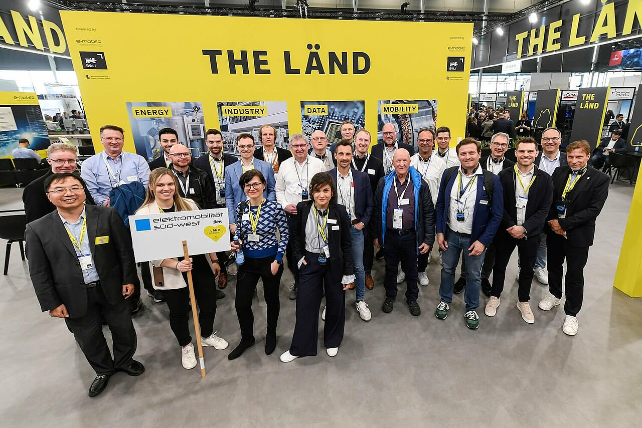 Eine Gruppe von Menschen vor einer gelbes Messewand auf der Hannover Messe.