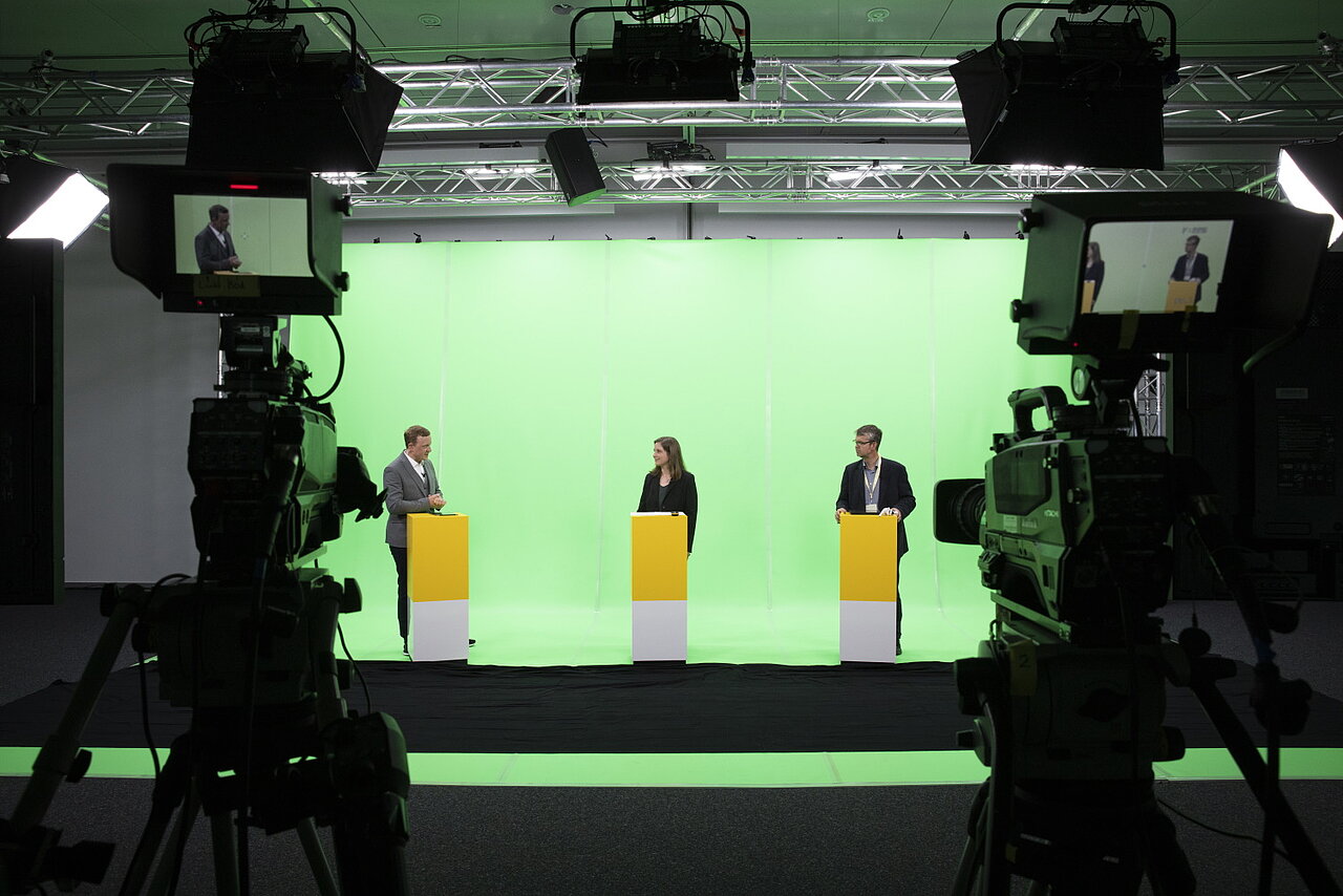 Ein Live-Stream wird aufgenommen mit drei Personen vor einem Green-Screen.