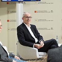 Portraitaufnahme von Hanns-Peter Becker, e&Co. AG, der auf einem Stuhl sitzt.