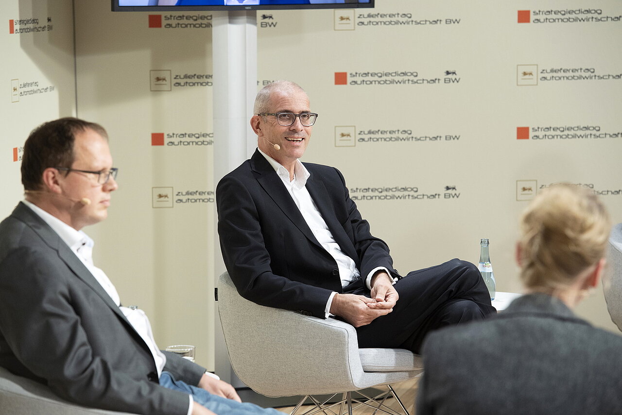 Portraitaufnahme von Hanns-Peter Becker, e&Co. AG, der auf einem Stuhl sitzt.