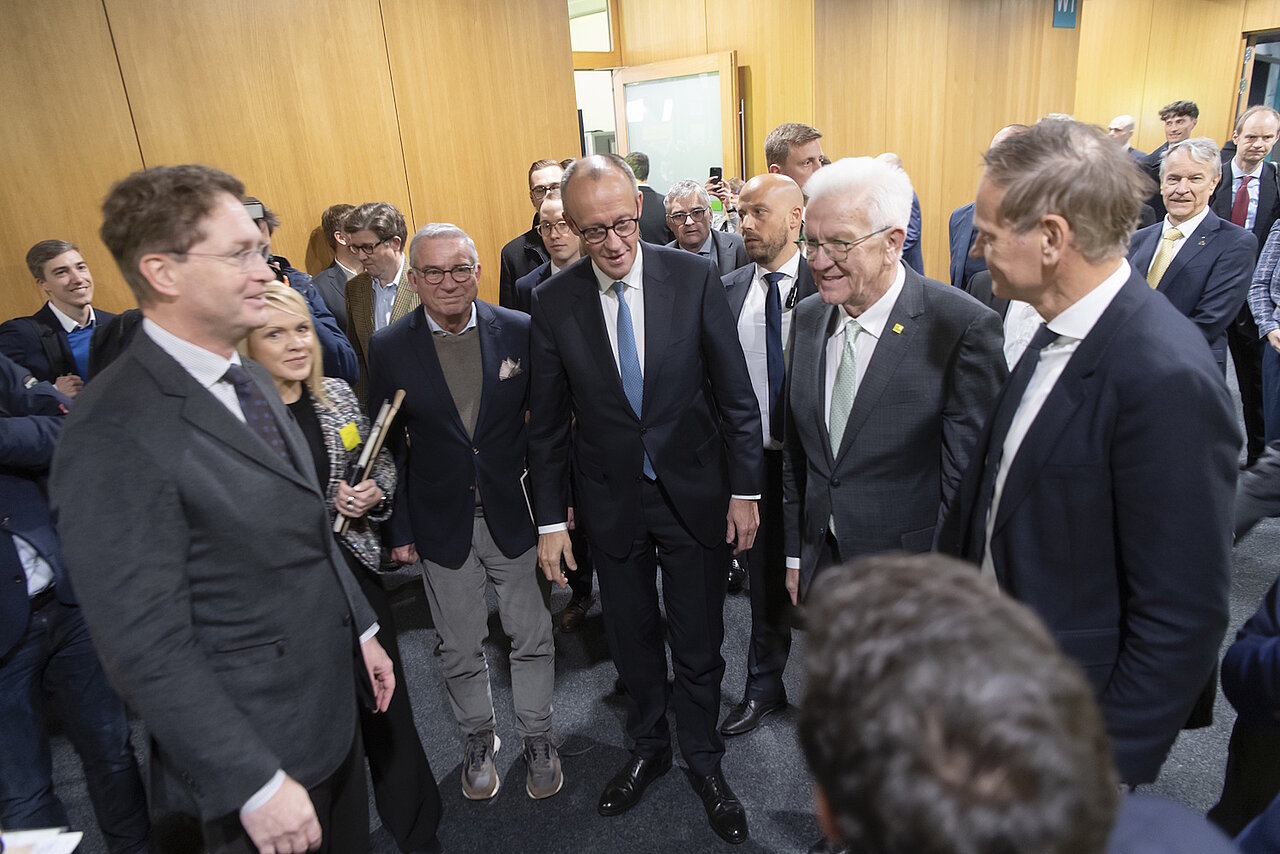 Bundeskanzler Friedrich Merz mit Ministerpräsident Winfried Kretschmann und Ola Källenius mit anderen Teilnehmern des Strategiedialog Automobilwirtschaft in Stuttgart stehen im Kreis zusammen.