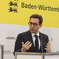 EU-Vizepräsident Stéphane Séjourné bei der Pressekonferenz des Strategiedialog Automobilwirtschaft BW vor einer gelben Wand.