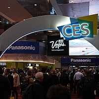 Messebogen zur CES 2020 in Las Vegas. Unter dem Bogen schlendern viele Besuchende über die Messe.