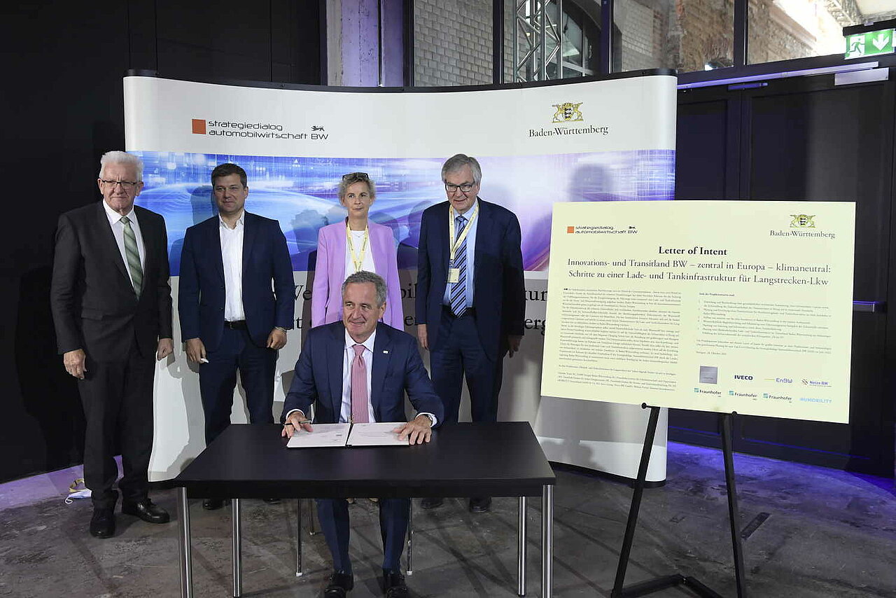 Ministerpräsident Kretschmann gemeinsam mit Wirtschaftsvertreter:innen unterzeichnen eine Absichtserklärung für ein „Pilot-Lade- und Wasserstoff-Tankinfrastrukturprojekt für Langstrecken-Lkw“.