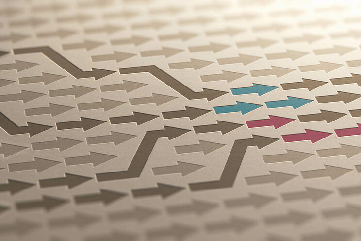 Viele braune Pfeile zeigen nach Rechts. In der Mitte sind einige dunkler eingefärbt und zeigen vier unterschiedliche Wege. Zwei dieser Wege enden jeweils in roten Pfeilen, die anderen zwei in blauen.