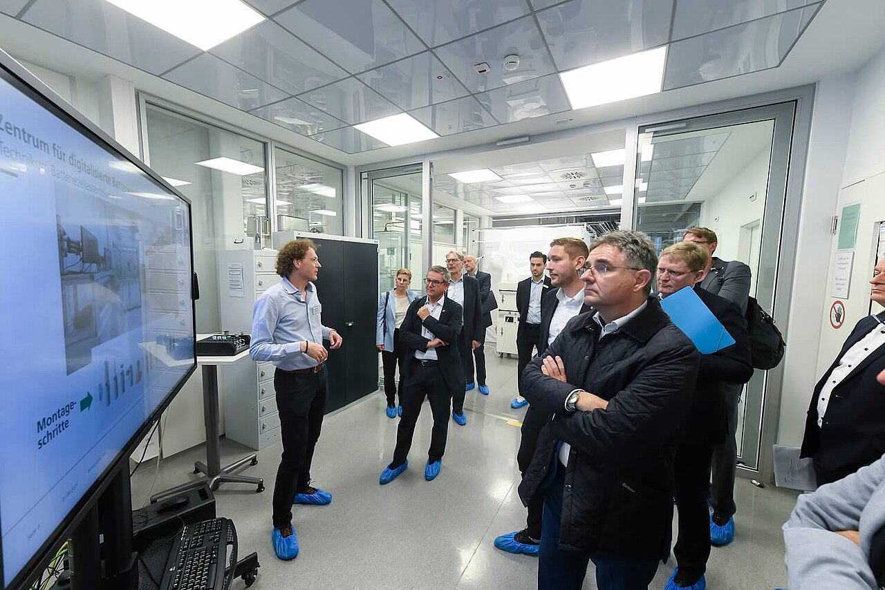 Ein Mann hält einen Vortrag. Das Publikum blickt auf den großen Bildschirm.