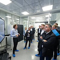 Ein Mann hält einen Vortrag. Das Publikum blickt auf den großen Bildschirm.