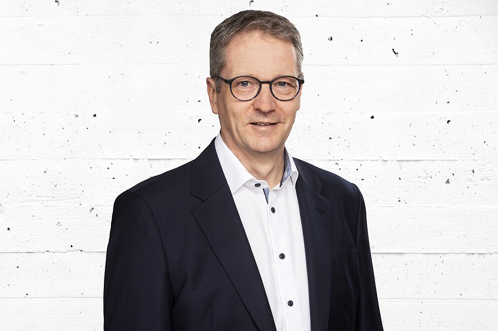 Porträt von Bernd Schneider Porträt von Bernd Schneider vor einer grauen Betonwand