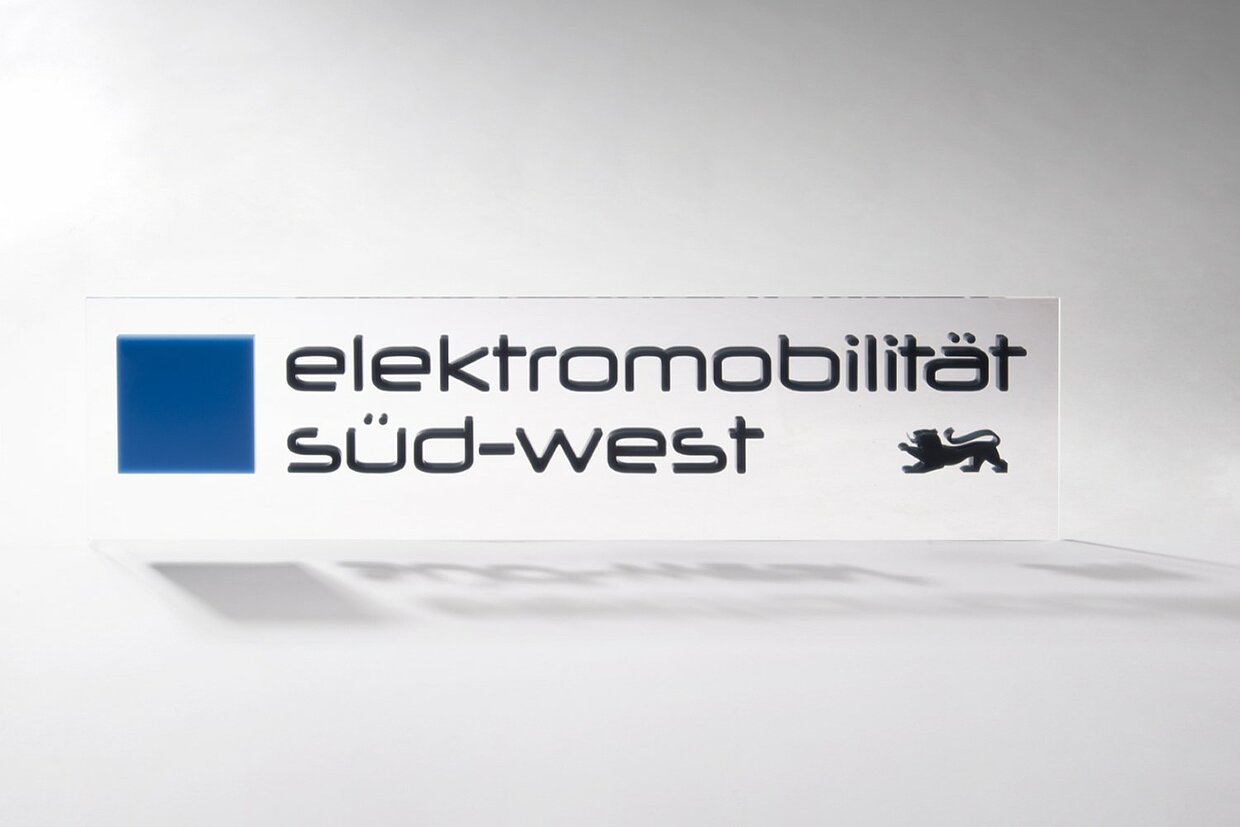 Das Logo des Clusters Elektromobilität Süd-West auf einer rechteckigen Plexiglasscheibe