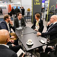 Ein Mitarbeiter und eine Mitarbeiterin sitzen am Tisch mit der finnischen Wirtschaftsförderung LADEC Lahti Region Development auf der Hannover Messe 2025.