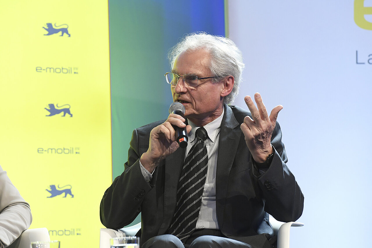 Prof. Dr. Henning Kagermann, Vorsitzender der Nationalen Plattform Zukunft der Mobilität (NPM) spricht in ein Mikrofon auf dem Podium.