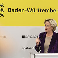 Ministerin Dr. Nicole Hoffmeister-Kraut bei der Pressekonferenz des Strategiedialog Automobilwirtschaft BW vor einer gelben Wand.