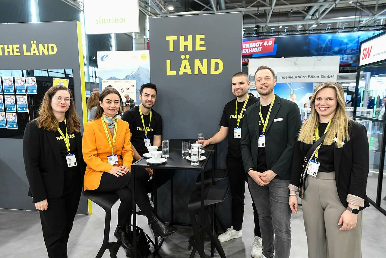 Sechs Mitarbeiterinnen und Mitarbeiter von e-mobil BW am Messestand des Baden-Württemberg Pavillons auf der Hannover Messe 2025.