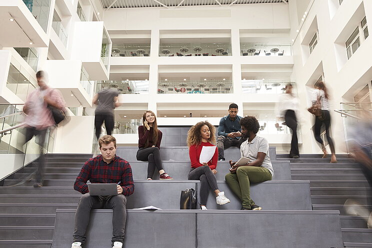 Junge Studierende sitzen auf den Treppen einer Hochschule Junge Studierende sitzen auf den Treppenstufen eine Hochschule