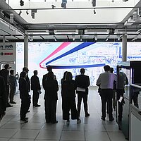 Eine Besuchergruppe blickt auf eine große LED-Wand.