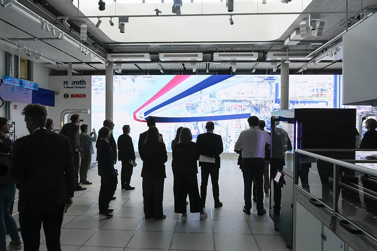 Eine Besuchergruppe blickt auf eine große LED-Wand.