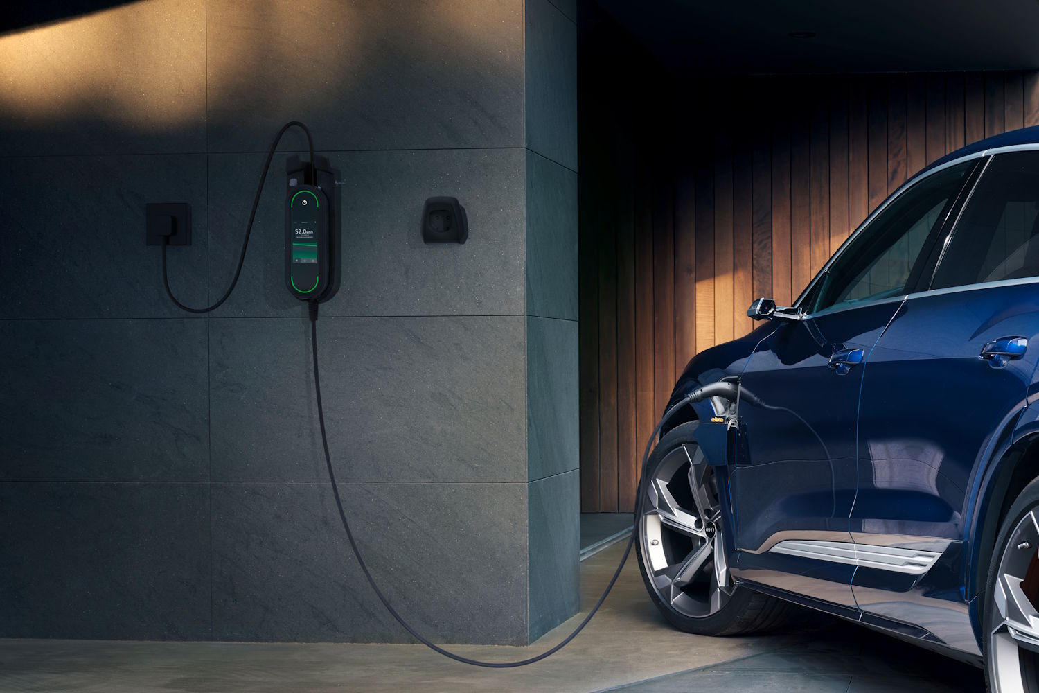 Ein blaues E-Auto steht in einer Garage und wird über eine Wallbox aufgeladen